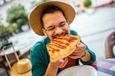 Lezzetli pizza yiyen yakışıklı bir gencin portresi..