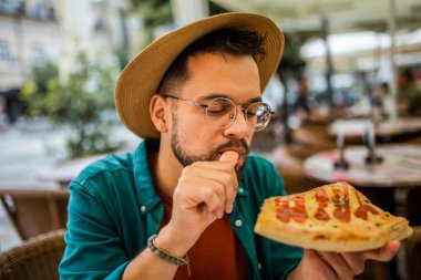 Lezzetli pizza yiyen yakışıklı bir gencin portresi..