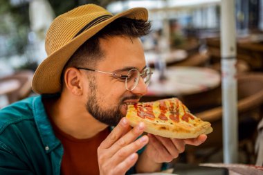 Lezzetli pizza yiyen yakışıklı bir gencin portresi..