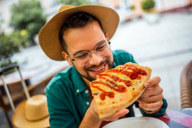 Lezzetli pizza yiyen yakışıklı bir gencin portresi..