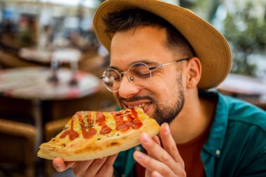 Lezzetli pizza yiyen yakışıklı bir gencin portresi..