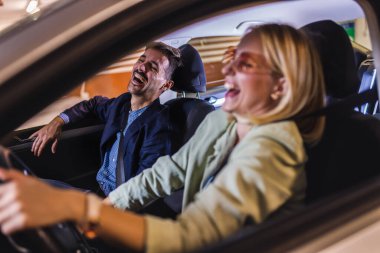 Mutlu, enerjik bir çift arabayla etrafta dolaşıyor. Gülümser ve şarkı söylerler..