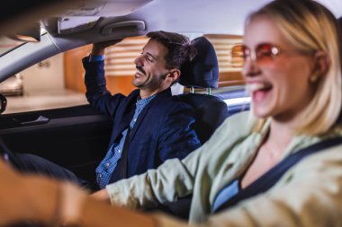 Mutlu, enerjik bir çift arabayla etrafta dolaşıyor. Gülümser ve şarkı söylerler..