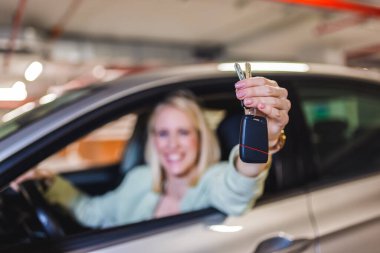 Yeni aldığı arabanın anahtarlarını gösteren mutlu sarışın kadın..