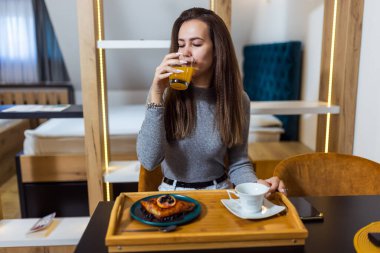 Evinde neşeli bir kadın tatlı yer ve portakal suyu içer..