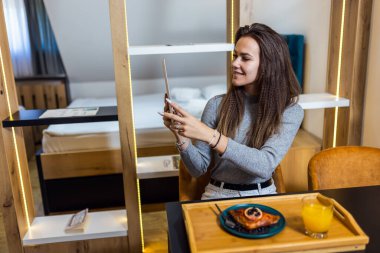 Mutlu kadın evinde nefis görünümlü turta yerken tabletle selfie çekiyor..