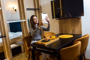 Mutlu kadın evinde nefis görünümlü turta yerken tabletle selfie çekiyor..