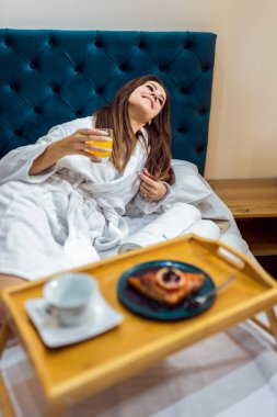 Güzel bir kadın otel odasında kahvaltısını yapıyor..