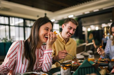 Bir grup mutlu arkadaş birlikte bir restoranda öğle yemeği yiyorlar. Lezzetli salatalar ve hamburgerler yerler.. 