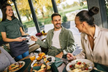 İnsanlar lokantada kredi kartıyla ödeme yapıyorlar..