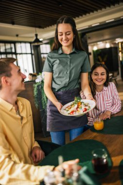 Garson, bir restorandaki misafirlerine sezar salatası olan ilk yemeği getirir..