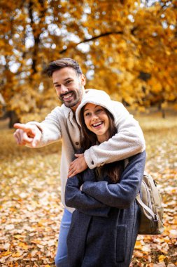 Genç mutlu çift parkta sarılıp yürüyor. Güneşli sonbahar gününde Renkli park.