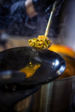 Mutfakta aşçı büyük tencerede yeşil bezelye, biftek, patates, soslu soğan pişiriyor..