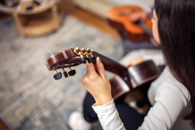 Evde gitar çalan genç bir kız.