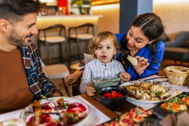 Üç kişilik bir aile lezzetli bir restoranda yemek yiyor. Yiyecek ve içecek konsepti.