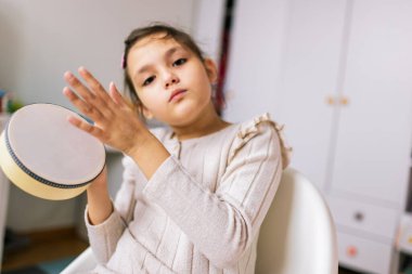 Otizmli küçük kız perküsyon aleti çalıyor. Evde müzik terapisi.