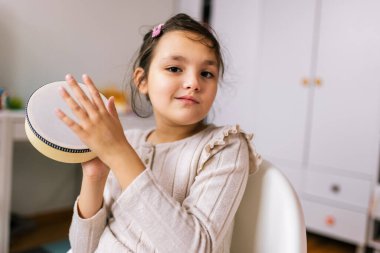 Otizmli küçük kız perküsyon aleti çalıyor. Evde müzik terapisi.