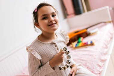 Otizmli küçük kız çan çalıyor. Evde müzik terapisi.