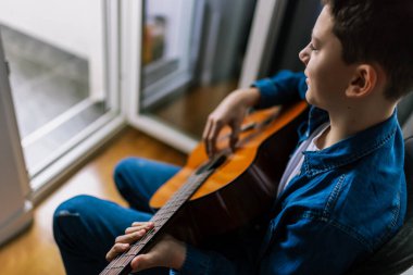 Çocuk evde gitar çalıyor..
