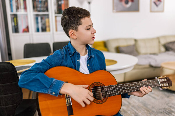 Boy plays guitar at home.