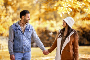 Genç mutlu çift parkta sarılıp yürüyor. Güneşli sonbahar gününde Renkli park.