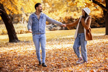 Genç mutlu çift parkta sarılıp yürüyor. Güneşli sonbahar gününde Renkli park.