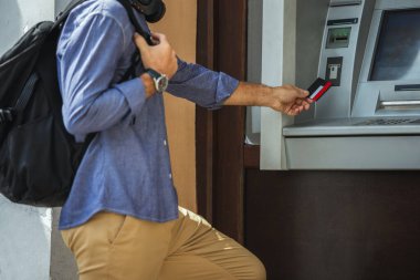 ATM makinesinin önünde kredi kartıyla duran yaşlı turist..