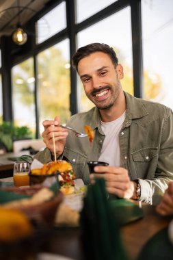 Man enjoying his lunch at a restaurant, sitting at a table with a delicious meal in front of him. clipart