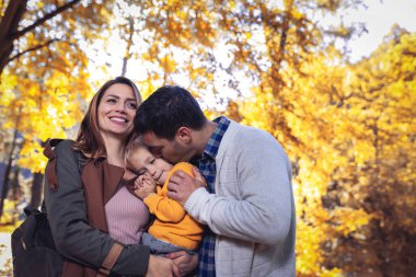 Güneşli bir günde, sonbahar parkında küçük oğlu olan genç bir aile. Aile sonbahar portresi