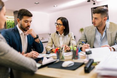 İşçi grubu ve takım lideri toplantı odasında iş yerinde takım çalışması tartışması yürütüyorlar..