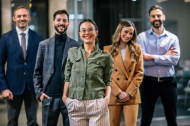 Modern bir ofis ortamında birlikte poz veren çeşitli profesyoneller..