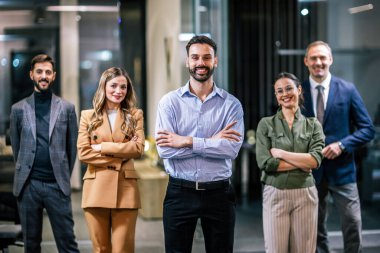 Modern bir ofis ortamında birlikte poz veren çeşitli profesyoneller..