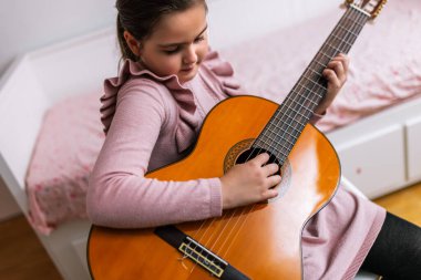 Mutlu küçük kız pembe odasında gitar çalıyor..