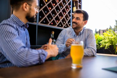İki erkek arkadaş restoranda takılıyor ve bira içiyor..