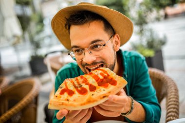 Lezzetli pizza yiyen yakışıklı bir gencin portresi..