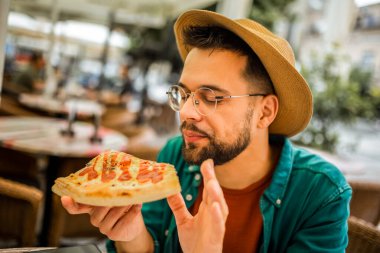 Lezzetli pizza yiyen yakışıklı bir gencin portresi..