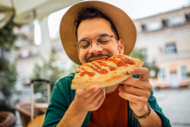 Lezzetli pizza yiyen yakışıklı bir gencin portresi..