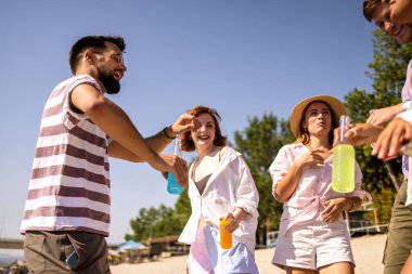 Bir grup arkadaş plajda takılıyorlar. Dans ve kokteyller..