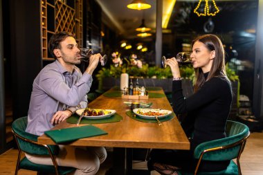 Genç, mutlu bir çift romantik bir buluşmada lüks bir restoranda kırmızı şarap içer. .