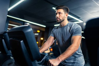Spor salonunda koşu bandında koşan kaslı genç adam..