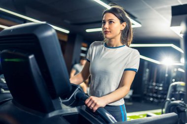 Kadın spor salonunda koşu bandında koşuyor..