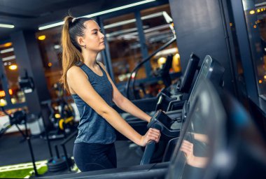 Kız spor salonunda koşu bandında yürüyor..