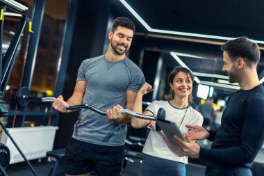 Arkadaşı onu cesaretlendirirken adam halter ağırlıklarıyla egzersiz yapıyor..