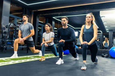 Spor salonunda grup çalışması yapan insanlar hamleler yapıyor..