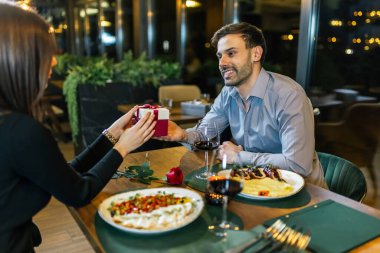 Romantik erkek arkadaş, güzel kız arkadaşına restoranda akşam yemeğinde hediye verir..