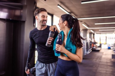Spor salonunda iki ortak su şişeleri ve havluyla yürüyor..