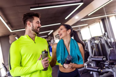 Spor salonunda iki ortak su şişeleri ve havluyla yürüyor..