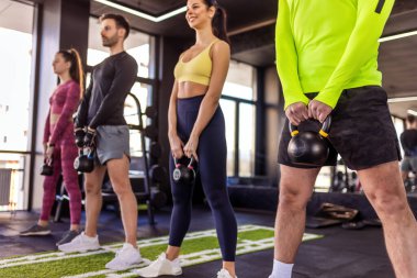 Bir grup insan dambıllarıyla ağırlıklı çömelme hareketleri yapıyor..