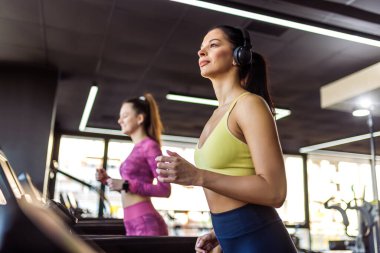 İki kadın koşu bandında koşuyor..