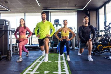 Spor salonunda grup çalışması yapan insanlar hamleler yapıyor..